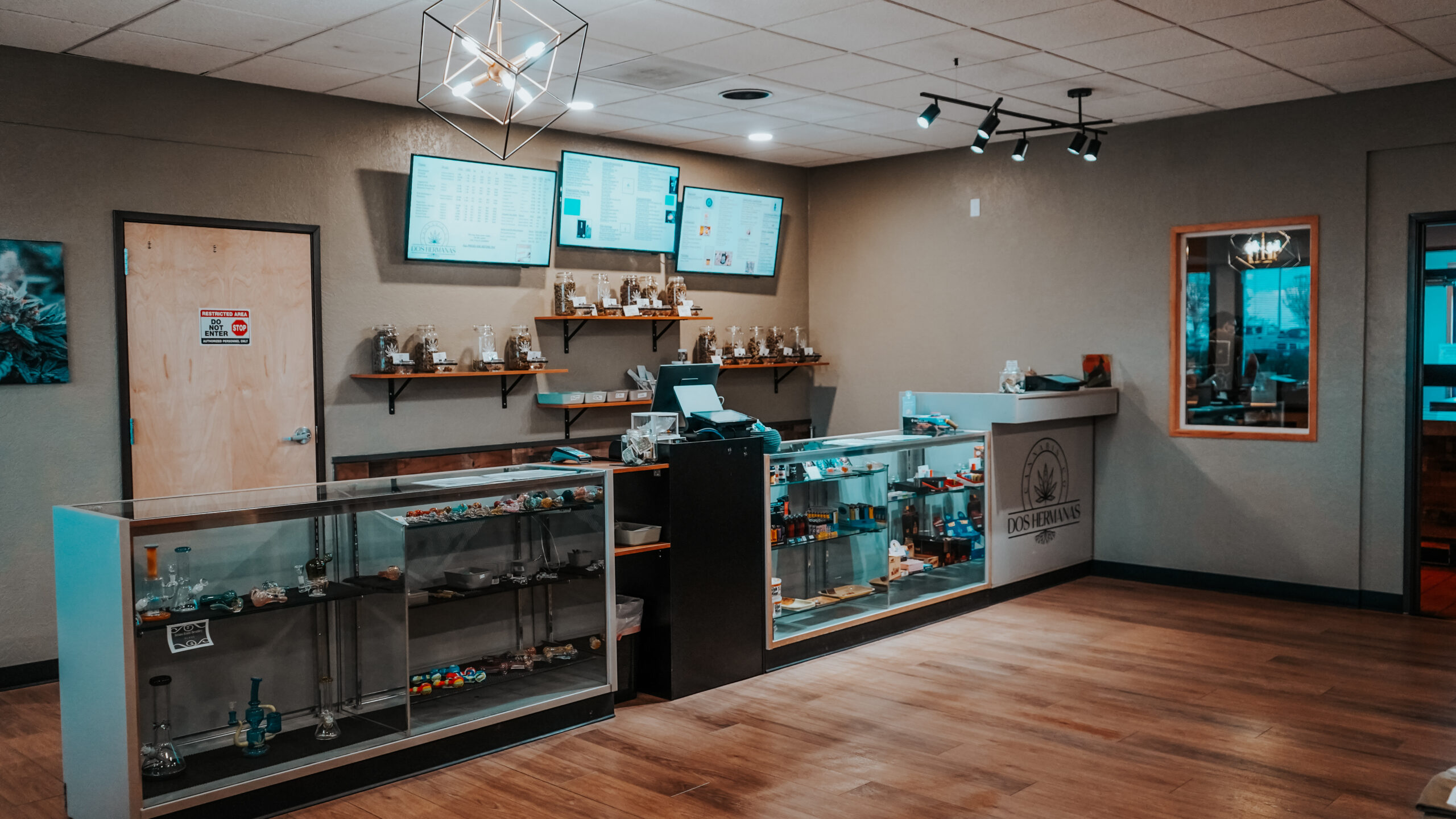 Sales floor at Dos Hermanas Canna Co dispensary in Santa Rosa, NM, with glass display cases and digital menu screens